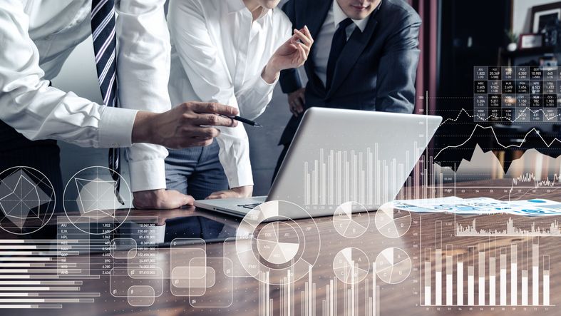 Liiketoimintatiimi analysoi luottoriskiä ja talousdataa kannettavalta tietokoneelta.